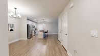 This 2-bedroom, 2-bathroom residence is designed with a clean, modern aesthetic and a functional open-concept layout. Light-toned luxury vinyl plank flooring flows seamlessly throughout the entire home, complemented by neutral wall tones and crisp white trim, creating a cohesive and contemporary feel.

The combined kitchen and living area serves as the heart of the home. The kitchen features stainless steel appliances, white cabinetry, granite countertops, and a central island with seating — illuminated by stylish pendant lighting overhead. The adjacent living room is bright and spacious, with a ceiling fan, large windows, and a glass door that opens to a private balcony, allowing abundant natural light to pour in.

The primary bedroom is generously sized, offering a ceiling fan and a well-organized walk-in closet equipped with wire shelving systems for ample storage. The en-suite primary bathroom includes a granite-topped vanity with grey cabinetry, a soaking tub, and a separate walk-in shower with glass enclosure.

The second bedroom is bright and comfortable, featuring a ceiling fan and a large window with outdoor views. A second full bathroom and an additional closet round out the home's thoughtfully planned layout, with clean hallways connecting each space efficiently.