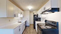 Located in Tualatin, Oregon, this two-bedroom, one-bathroom residence offers a practical and well-organized single-floor layout. The galley-style kitchen is a standout feature, showcasing updated white shaker cabinetry with black hardware, white countertops, wood-look flooring, and black appliances including a refrigerator, electric range with overhead ventilation, and dishwasher — all topped with a textured ceiling finish. Adjacent to the kitchen is a dining area with wood-look flooring, white cabinetry, a window overlooking greenery, and a baseboard heater. The living room is carpeted and features a sliding glass door that opens to a private balcony with outdoor views, filling the space with natural light. Both bedrooms are carpeted and include baseboard heating and windows that bring in natural light; the primary bedroom offers a closet with a built-in shelf. The full bathroom is finished with wood-look flooring, a tub/shower combination, a white vanity with countertop, and a chrome grab bar. Throughout the unit, textured ceilings and neutral wall tones create a clean, cohesive aesthetic.