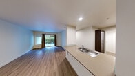 Located along West Lake Sammamish Parkway in Issaquah, WA, this two-bedroom, two-bathroom residence offers a well-designed single-floor layout. The open-concept living and kitchen area is anchored by warm wood-style flooring and recessed lighting. The kitchen features dark wood cabinetry, light countertops, stainless steel appliances including a dishwasher and microwave, and a double-basin sink with a breakfast bar that opens to the living space. The living room is bright and airy, with a sliding glass door and adjacent window framing views of lush outdoor greenery, allowing ample natural light to fill the space. Both bedrooms are carpeted and equipped with ceiling fans; the primary bedroom includes a window overlooking the natural surroundings. The primary bathroom offers a dual-sink vanity with dark wood cabinetry, a large mirror, and track lighting, while the second bathroom features a combined tub and shower. A dedicated laundry area and closet add to the unit's practicality. Clean white walls, consistent flooring materials, and a neutral palette throughout create a cohesive, move-in-ready atmosphere.
