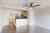 Located at 6555 La Mirada Ave in the heart of Los Angeles, CA, this efficiently laid-out single-floor unit makes smart use of its space with a thoughtful open-concept design. The combined kitchen and living area serves as the central hub of the home, featuring smooth hardwood-style flooring, crisp white walls, and a textured ceiling with a modern ceiling fan that provides both style and airflow. A large sliding window in the living area invites natural light, creating a bright and airy atmosphere. The kitchen is well-appointed with white shaker cabinetry, stainless steel appliances including a gas range, microwave, and refrigerator, complemented by a striking patterned tile backsplash that adds a bold decorative touch. A peninsula counter provides additional workspace and casual dining space. The unit includes two bathrooms: one features a sleek, frameless glass-door shower enclosure, while the other showcases white vanity cabinetry with a framed mirror and contemporary lighting. A mirrored sliding closet door enhances the sense of space. The unit also includes a wall-mounted A/C unit for climate control. Clean finishes, modern fixtures, and a cohesive neutral palette give the space a polished, move-in-ready feel.