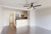 Located at 6555 La Mirada Ave in the heart of Los Angeles, CA, this efficiently laid-out single-floor unit makes smart use of its space with a thoughtful open-concept design. The combined kitchen and living area serves as the central hub of the home, featuring smooth hardwood-style flooring, crisp white walls, and a textured ceiling with a modern ceiling fan that provides both style and airflow. A large sliding window in the living area invites natural light, creating a bright and airy atmosphere. The kitchen is well-appointed with white shaker cabinetry, stainless steel appliances including a gas range, microwave, and refrigerator, complemented by a striking patterned tile backsplash that adds a bold decorative touch. A peninsula counter provides additional workspace and casual dining space. The unit includes two bathrooms: one features a sleek, frameless glass-door shower enclosure, while the other showcases white vanity cabinetry with a framed mirror and contemporary lighting. A mirrored sliding closet door enhances the sense of space. The unit also includes a wall-mounted A/C unit for climate control. Clean finishes, modern fixtures, and a cohesive neutral palette give the space a polished, move-in-ready feel.