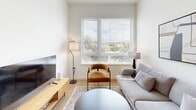 Located at 100 Callan Ave in San Leandro, CA, this well-designed 2-bedroom, 1-bathroom unit offers a thoughtfully laid-out single-floor plan with a clean, modern aesthetic throughout. The kitchen is a standout feature, showcasing rich walnut-toned cabinetry that extends to the ceiling, stainless steel appliances including a refrigerator, electric range, over-the-range microwave, and dishwasher, complemented by white quartz countertops and a classic subway tile backsplash. The adjacent dining area provides a seamless transition for everyday living and entertaining. The living room is bathed in natural light through a large picture window that frames pleasant outdoor views of the surrounding landscape, creating an inviting and airy atmosphere. Light wood-style flooring flows throughout the main living areas, adding warmth and continuity. The primary bedroom is a serene retreat with a natural light window, while the second bedroom offers a similarly calm, neutral aesthetic. The shared bathroom features wood-toned vanity cabinetry, white quartz countertops, a full tub-shower combination, and light wood-style flooring. Additional functional spaces include a laundry area, hallway, and multiple closets, ensuring ample storage throughout this efficiently designed home.