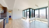 Located in the heart of downtown San Diego, this high-rise unit at 310 A St offers a sleek, contemporary living experience defined by abundant natural light and sweeping panoramic city views. The open living area is anchored by a dramatic corner configuration of floor-to-ceiling windows with dark-framed mullions, flooding the space with sunlight and framing striking skyline vistas. Light-toned wood-style flooring runs throughout, lending a clean, cohesive aesthetic to every room.

The kitchen is outfitted with warm wood cabinetry, a marble-style backsplash, light stone countertops, and a full suite of stainless steel appliances including a gas range, over-the-range microwave, and French door refrigerator. The bedroom continues the floor-to-ceiling window theme, offering direct city views and access to a balcony, with recessed lighting overhead and ample closet space.

The bathroom features large-format marble-look tile on both the floor and tub surround, paired with polished chrome fixtures for a refined, spa-like feel. An additional walk-in closet with built-in shelving and hanging rods provides generous storage. Throughout, the unit's crisp white walls and minimalist design create a bright, airy ambiance that complements the vibrant urban setting of San Diego's downtown core.