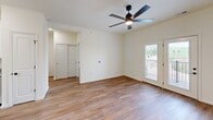 Located at 100 Bricks Hill Rd in O'Fallon, Missouri, this one-bedroom, one-bathroom unit offers a well-designed single-level layout with consistent wood-look flooring and neutral tones throughout. The combined kitchen and living area serves as the heart of the home, featuring white shaker-style cabinetry, granite countertops, a center island, and a full suite of stainless steel appliances including a refrigerator, range, microwave, and dishwasher. Recessed lighting brightens the kitchen, while the living area is equipped with a ceiling fan and French doors that open to a private balcony with outdoor views. The spacious bedroom offers a ceiling fan, a large window for natural light, and direct access to the hallway. The bathroom is finished with a granite-topped vanity, a walk-in glass-enclosed shower, and matching wood-look flooring that ties the space together. A dedicated laundry area houses a full-size Whirlpool top-load washer and dryer with overhead wire shelving for additional storage. A separate closet and hallway complete the layout, providing practical everyday functionality. The clean, modern finishes and thoughtful design make this a comfortable and efficient living space.