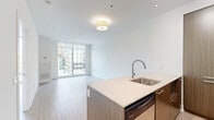 Located at 310 Tweedsmuir Ave in Toronto's sought-after Forest Hill neighbourhood, this well-appointed one-bedroom unit offers a thoughtfully designed open-concept layout. Light hardwood flooring flows seamlessly throughout the entire space, contributing to a clean, contemporary aesthetic anchored by crisp white walls and abundant natural light.

The kitchen and living area form a cohesive open space ideal for both daily living and entertaining. The kitchen is a standout feature, boasting warm wood-grain cabinetry, a large central island with an undermount sink and light quartz countertop, a tile backsplash, and stainless steel appliances including a refrigerator, oven, and dishwasher. Track lighting overhead illuminates the workspace effectively.

Floor-to-ceiling windows in the living area and bedroom frame views of the surrounding Toronto skyline and tree-lined streetscape, filling the unit with generous natural light throughout the day. The bedroom is a comfortable, well-proportioned retreat featuring mirrored sliding closet doors that enhance the sense of space and reflect incoming light.

The overall ambiance is modern and minimalist, with a neutral palette and high-quality finishes that create a bright, airy atmosphere throughout the unit.