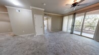 Located at 6200 Montano Plaza Dr NW in Albuquerque, New Mexico, this 2-bedroom, 2-bathroom single-floor residence offers a well-organized layout designed for comfortable everyday living. The living room is generously sized, finished with plush carpeting, crown molding, and a ceiling fan. Sliding glass doors open directly onto a private balcony overlooking mature trees, bringing in natural light and outdoor views. The kitchen is functional and well-appointed, featuring light wood cabinetry, dark countertops, black appliances including a refrigerator, gas range, and microwave, a peninsula breakfast bar, and track lighting overhead. Wood-look flooring runs through the kitchen and connects seamlessly to the adjacent laundry area, which includes a full-size washer and dryer. The spacious primary bedroom offers abundant natural light through sliding doors to the balcony, a ceiling fan, and access to a dedicated closet. The second bedroom is bright and well-lit with two windows and its own closet. Both bathrooms are finished with white tile tub-surround surrounds featuring diamond-pattern taupe tile accents, wood-look flooring, and warm wood vanities. A hallway connects the bedrooms and bathrooms, maintaining a clear and practical flow throughout the home.