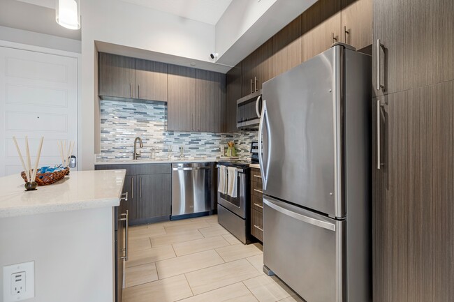 Model kitchen and dining room at our apartments in Boca Raton, featuring chairs around a table and counter seating. - Boca City Walk