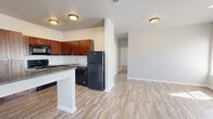 This single-story, 2-bedroom, 2-bathroom residence offers a thoughtfully designed layout that maximizes comfort and functionality. Light wood-look flooring flows consistently throughout the entire unit, creating a cohesive and clean aesthetic. The open-concept living area is anchored by a front entry with large windows that invite abundant natural light, lending the space a bright and airy feel.

The kitchen is a standout feature, equipped with rich dark wood cabinetry, dark granite-style countertops, a white subway tile backsplash, and black appliances including a refrigerator, electric range, built-in microwave, and dishwasher. A peninsula with a dark countertop provides additional workspace and separates the kitchen from the combined dining and living area.

Both bedrooms are comfortably sized and filled with natural light from well-positioned windows. The spacious primary bedroom includes its own dedicated closet. The secondary bedroom is equally bright and versatile. Each bedroom is served by its own bathroom — one featuring a rich wood vanity with granite countertop and a tub/shower combination, and the second a clean, functional tub/shower setup. Two closets provide ample storage throughout the unit. Neutral gray walls and clean white trim complete the modern, move-in-ready aesthetic.