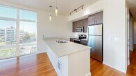 Located in Seattle's Capitol Hill neighborhood, this thoughtfully designed one-bedroom, one-bathroom residence offers a clean, modern aesthetic across a single floor. Warm hardwood flooring flows throughout the living areas, complementing the crisp white walls and creating a welcoming atmosphere.

The open-concept kitchen and living area serves as the heart of the home. The kitchen is outfitted with stainless steel appliances — including a range, microwave, and full-size refrigerator — paired with warm wood cabinetry and stone-finish countertops. A peninsula with an undermount sink provides additional prep space and serves as a natural divider between the kitchen and living area. Pendant lighting and track lighting add functional style overhead.

The living room is bathed in natural light thanks to expansive floor-to-ceiling windows that frame sweeping views of the Seattle skyline and surrounding cityscape, extending the sense of space well beyond the interior.

The bedroom is a quiet, well-proportioned retreat, also benefiting from large windows with city views and hardwood flooring. Two closets provide ample storage.

The bathroom features a wood-toned vanity with stone-finish countertops, an undermount sink, and large mirrors that reflect light throughout the space. Sliding doors and recessed lighting add to the unit's clean, contemporary finish.