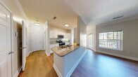 Located at 499 Boston Rd in Billerica, MA, this one-bedroom, one-bathroom residence offers a well-designed, efficient layout across a single floor. The open-concept living area seamlessly integrates the kitchen, dining room, and living room, creating a bright and cohesive space. The kitchen features a peninsula with a granite-style countertop, stainless steel appliances including a range, microwave, refrigerator, and dishwasher, complemented by white shaker cabinetry and warm hardwood-style flooring throughout. A pendant light fixture adds a refined touch to the dining area. The living room is generously sized, filled with natural light from large windows and a glass balcony door that opens to a private outdoor balcony with views of surrounding greenery. The bedroom is a comfortable retreat with plush carpeting, a large window overlooking lush foliage, and access to two closets, including a spacious walk-in outfitted with wire shelving. The full bathroom offers a white vanity with storage, a large mirror, and a tiled tub-shower combination with hardwood-style flooring. Additional highlights include a dedicated laundry area and a hallway connecting the living spaces, making this a functional and inviting home.