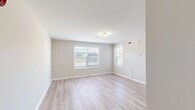 This single-floor unit offers a well-organized and functional layout designed for comfortable everyday living. Throughout the space, light hardwood-style flooring and neutral beige walls create a bright, cohesive aesthetic that feels open and welcoming.

The living area is generously proportioned, featuring multiple windows fitted with horizontal blinds that allow for abundant natural light and views of the surrounding outdoor greenery. Wall-mounted vents and a thermostat reflect practical climate control throughout.

The kitchen is equipped with warm honey-toned wood cabinetry providing ample storage, a double-basin sink, a full suite of white appliances including a refrigerator, electric range with overhead microwave, and dishwasher. A peninsula counter extends into the space, offering additional workspace and a natural transition to the living area.

The bedrooms are well-sized, each with light flooring, neutral walls, and windows that bring in natural light. At least one bedroom includes a dedicated closet with a hanging rod, offering practical storage. An additional room also benefits from natural light via exterior-facing windows.

The bathroom features warm-toned tile flooring, clean white fixtures, and a towel bar, maintaining the unit's consistent, functional design. Overall, the space presents a clean, move-in-ready environment with a bright and neutral palette throughout.