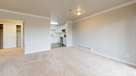 This single-floor residence offers a thoughtfully designed layout that balances comfort and functionality throughout its living spaces. The open-concept living area is finished with plush neutral carpet and crowned with elegant crown molding that runs consistently throughout, lending a polished character to every room. A baseboard heating system is installed along the walls, ensuring year-round comfort. Large windows dressed with vertical blinds flood the living spaces with natural light and provide views of the surrounding greenery outside.

The kitchen is a standout feature, showcasing white shaker-style cabinetry paired with crisp white quartz countertops and a classic subway tile backsplash. Stainless steel appliances, including a range, microwave, and dishwasher, complement the deep undermount sink with a brushed nickel pull-down faucet. Wood-look luxury vinyl flooring grounds the kitchen and flows into adjoining areas seamlessly.

The bedroom is generously proportioned, finished with the same soft carpet and crown molding found throughout, and offers direct access to the bathroom. The bathroom features a full tub and shower combination enclosed by frosted sliding glass doors with chrome hardware, a clean white toilet, and wood-look vinyl flooring that ties the space together. The overall ambiance is clean, neutral, and move-in ready.