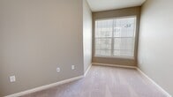 Located in Clinton, Mississippi, this well-designed 2-bedroom, 1-bathroom unit offers a practical and modern layout across a single floor. The open-concept kitchen and living area serves as the heart of the home, featuring wood-look luxury vinyl plank flooring, recessed and track lighting, and a kitchen peninsula with a sink and light countertops. The kitchen is equipped with white shaker-style cabinetry, a subway tile backsplash, stainless steel appliances including a refrigerator, range, and microwave, creating a clean and contemporary aesthetic. French doors with transom windows flood the living area with natural light and provide access to the outdoors. The two bedrooms are finished with plush wall-to-wall carpeting and large windows fitted with horizontal blinds. The primary bedroom includes a spacious walk-in closet with wire shelving for ample storage. The bathroom features a white vanity with a undermount sink, brushed nickel fixtures, and a framed mirror. A hallway with an electrical panel provides access to an in-unit washer, adding convenience. Neutral warm-gray walls throughout create a cohesive, move-in-ready atmosphere.