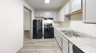 This single-floor unit at 4111 Glenwood Ave in Youngstown, Ohio presents a clean, updated interior with a consistent neutral color palette and light wood-look flooring carried throughout every room. The layout, as seen in the floor plan overview, is thoughtfully arranged to connect living, kitchen, sleeping, and bathroom areas in a practical flow.

The living area is generously proportioned, featuring a ceiling fan with light fixture, baseboard heating, and a wall-mounted air conditioning unit for year-round climate control. Vertical blinds cover a large sliding glass door that allows natural light to fill the space. The room connects openly to the rest of the unit, creating an airy, accessible feel.

The kitchen is well-appointed with gray shaker-style cabinetry, light granite-look countertops, a double stainless steel sink, and black appliances including a refrigerator, electric range, and dishwasher. Overhead lighting keeps the space bright and functional.

The bedrooms are comfortably sized, each with ceiling-mounted light fixtures, baseboard heating, and windows that bring in natural light. The bathroom includes a white vanity with cabinetry, a large mirror, a tub-shower combination, and consistent light flooring, maintaining the unit's clean aesthetic throughout.