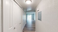 This single-story residence offers a thoughtfully arranged floor plan with a clean, updated aesthetic throughout. A central hallway connects the main living areas, lined with white bi-fold closet doors and wood-look vinyl plank flooring that extends through much of the home. A ceiling fan and sliding glass door anchor the main living area, which receives generous natural light through vertical blinds and opens to an outdoor view.

The kitchen features white shaker-style cabinetry, a subway tile backsplash, light countertops, a stainless steel dishwasher, and a single-basin sink — creating a bright, functional workspace. The layout flows openly toward the adjoining living spaces.

Bedrooms vary in flooring, with at least one room finished in plush carpet and equipped with a ceiling fan, while another offers wood-look flooring and closet access. Each bedroom benefits from natural light via windows dressed with vertical blinds.

Two bathrooms are present. One includes a vanity with white cabinetry, a framed mirror, and a tub/shower combination enclosed by sliding glass doors with subway tile surround. The second bathroom features a standalone walk-in shower with matching subway tile and a sliding frosted glass enclosure. Both bathrooms include wood-look flooring and clean, neutral finishes throughout.