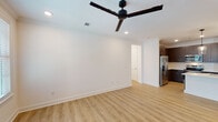 This thoughtfully designed single-story, 3-bedroom, 2-bathroom home features a cohesive modern aesthetic carried throughout its open-concept layout. Light wood-look flooring flows seamlessly across the living, dining, and kitchen areas, creating a bright and airy atmosphere complemented by recessed lighting and crown molding.

The kitchen is a standout feature, showcasing rich dark cabinetry with sleek hardware, white quartz countertops, a subway tile backsplash, and a full suite of stainless steel appliances including a French door refrigerator, electric range, and over-the-range microwave. A central island with an undermount sink and stylish pendant lighting serves as the focal point, ideal for both meal prep and casual dining. Built-in shelving adds additional display and storage space nearby.

The open living area is generously sized, featuring a modern ceiling fan and easy access to the entryway. Each bedroom offers light wood flooring, ceiling fans, and natural light from windows with blinds. The two bathrooms are well-appointed — one featuring a dual-sink vanity with dark cabinetry and quartz countertops with a large framed mirror, and the other offering a tiled walk-in shower with a glass door and quartz vanity. The home presents a clean, move-in-ready interior with consistent, contemporary finishes throughout.