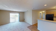 This single-floor residence offers a practical and comfortable layout designed for everyday living. The open-concept living and dining area is highlighted by a combination of hardwood-style flooring and plush carpeting, with a sliding glass door that leads to a private balcony, filling the space with natural light and views of the surrounding greenery. A half-wall peninsula separates the living area from the kitchen, creating a natural flow between the two spaces.

The U-shaped kitchen is well-equipped with ample light wood cabinetry, generous countertop space, a stainless steel sink, and black appliances including a gas range and refrigerator. The layout provides efficient use of space and ample storage for everyday needs.

The residence includes multiple bedrooms, each finished with soft wall-to-wall carpeting and windows that bring in natural light. One bedroom features a spacious closet with built-in shelving, offering practical storage solutions. The neutral, warm-toned walls throughout create a calm and inviting ambiance.

The bathroom is cleanly appointed with a single-sink vanity, a soaking tub and shower combination, and tile flooring. Conveniently located adjacent to the bathroom is an in-unit washer, adding ease to daily routines. Textured ceilings and consistent neutral finishes tie the entire residence together cohesively.