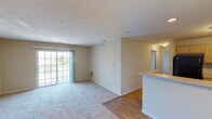 This single-floor residence offers a practical and comfortable layout designed for everyday living. The open-concept living and dining area is highlighted by a combination of hardwood-style flooring and plush carpeting, with a sliding glass door that leads to a private balcony, filling the space with natural light and views of the surrounding greenery. A half-wall peninsula separates the living area from the kitchen, creating a natural flow between the two spaces.

The U-shaped kitchen is well-equipped with ample light wood cabinetry, generous countertop space, a stainless steel sink, and black appliances including a gas range and refrigerator. The layout provides efficient use of space and ample storage for everyday needs.

The residence includes multiple bedrooms, each finished with soft wall-to-wall carpeting and windows that bring in natural light. One bedroom features a spacious closet with built-in shelving, offering practical storage solutions. The neutral, warm-toned walls throughout create a calm and inviting ambiance.

The bathroom is cleanly appointed with a single-sink vanity, a soaking tub and shower combination, and tile flooring. Conveniently located adjacent to the bathroom is an in-unit washer, adding ease to daily routines. Textured ceilings and consistent neutral finishes tie the entire residence together cohesively.