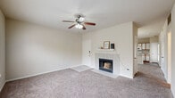 This single-floor residence offers a well-organized layout designed for comfortable everyday living. The living room serves as the heart of the home, centered around a classic tile-surround fireplace with a white mantel, soft carpeting underfoot, and a ceiling fan overhead that enhances air circulation throughout the space. Large windows allow natural light to filter in, offering views of the surrounding greenery and creating a bright, welcoming atmosphere.

The kitchen is thoughtfully designed with an open-concept layout that connects seamlessly to the living area via a peninsula breakfast bar with a double basin sink and speckled countertops. Warm wood-toned cabinetry pairs with white appliances, including an electric range, built-in microwave, and refrigerator, while track lighting and hardwood-style flooring add a practical, clean aesthetic. A door from the kitchen provides convenient exterior access.

The bedrooms are generously proportioned, each featuring plush carpeting, ceiling fans with light fixtures, and windows that invite natural light and outdoor views. The neutral wall tones throughout contribute to a calm, versatile ambiance.

Two full bathrooms complete the layout — one featuring a walk-in shower with a framed glass enclosure, and the other offering a full tub-shower combination. Both bathrooms include wood-toned vanities with speckled countertops and hardwood-style flooring.