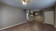 This single-floor residence offers a well-organized layout with a comfortable, neutral aesthetic throughout. The main living area features rich, dark hardwood-style flooring, warm taupe walls, and a textured ceiling. A ceiling fan with lighting illuminates the space, while a classic fireplace with a dark surround serves as a focal point. Natural light filters in through blinded windows, enhancing the welcoming ambiance. The living area flows seamlessly into a designated dining space, accented by a stylish pendant light fixture.

The galley-style kitchen is efficiently designed with white cabinetry, granite-look countertops, a stainless steel sink, and white appliances, including a full-size refrigerator and dishwasher. A pass-through counter connects the kitchen to the dining area, promoting an open feel.

The bedrooms are carpeted and generously sized, each equipped with a ceiling fan and window with blinds for natural light and privacy. The bathrooms are clean and functional — one features a full tub-shower combo with a white surround and dark hardware accents, while the other includes a vanity with stone-look countertops. A walk-in closet is accessible from the primary bathroom area, adding practical storage to the residence.