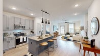 Located at 4535 SW 54th St Rd in Ocala, Florida, this well-appointed two-bedroom, two-bathroom residence offers a thoughtfully designed single-floor layout that maximizes both functionality and style. The open-concept kitchen and living area serves as the heart of the home, where light wood-look flooring, recessed lighting, and a ceiling fan create a bright, airy atmosphere. The kitchen is equipped with stainless steel appliances, gray shaker-style cabinetry, a white subway tile backsplash, granite countertops, and a large center island with pendant lighting and bar seating — ideal for both meal preparation and casual dining. A dedicated pantry provides additional storage convenience. The living room benefits from natural light streaming through multiple windows and a glass door that opens to an outdoor area. The primary bedroom is a comfortable retreat featuring plush carpeting, a ceiling fan, and a window overlooking the outdoors. Its en-suite bathroom includes a dual-sink vanity with granite countertops and gray cabinetry, plus a walk-in closet outfitted with wire shelving and hanging rods. The second bedroom is equally well-sized with carpeted floors and ample natural light. Three closets total, a dedicated laundry area, and a pantry round out the practical storage offerings throughout this modern, move-in-ready home.