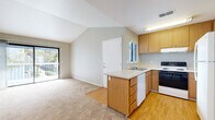 Located at 1100 E Leland Rd in Pittsburg, CA, this one-bedroom, one-bathroom unit offers a well-organized layout across a single floor. The living and dining area is bright and open, highlighted by soaring vaulted ceilings and soft carpeting underfoot. A sliding glass door floods the space with natural light and leads to a private balcony overlooking the surrounding greenery, creating a seamless indoor-outdoor connection.

The kitchen is efficiently designed with warm honey-toned cabinetry, a peninsula island with a built-in sink and dishwasher, a range, and a full-size refrigerator. Light hardwood-style flooring extends throughout the kitchen, transitioning to plush carpet in the living areas. The kitchen opens directly to the combined living and dining space, supporting an easy flow for daily living.

The spacious bedroom features vaulted ceilings, a ceiling fan, a closet, and a window that invites natural light. The full bathroom includes a single-sink vanity with wood cabinetry, a large mirror, and a tub-shower combination with clean white finishes and hardwood-style flooring. Additional highlights include two closets, a dedicated laundry area, a utility room, and ample storage throughout.