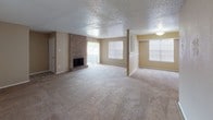 This single-story residence offers a practical and comfortable layout across several well-defined living spaces. The open living and dining area is a standout, featuring a full brick fireplace as a focal point, plush carpeting, a textured ceiling, and multiple windows that allow natural light to fill the space generously.

The galley-style kitchen is efficiently organized with cream-toned cabinetry, laminate countertops, a stainless steel sink, and white appliances including a coil-burner range and refrigerator. Tile flooring and a window at the end of the kitchen add brightness to the workspace.

The bedrooms are carpeted and equipped with ceiling fans and closets. One bedroom features a built-in vanity with a large mirror, dedicated lighting, and integrated cabinetry, offering added functionality. Each bedroom includes window blinds for privacy and natural light control.

The bathrooms are finished with warm-toned tile tub surrounds, combination tub-shower fixtures, tile flooring in a grid pattern, and vanities topped with speckled countertops. A wide mirror above the primary bathroom vanity enhances the sense of space. Throughout the unit, neutral warm tones create a cohesive and understated aesthetic.