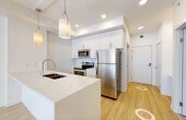 Located at 1790 Keene Cres SW in Edmonton's southwest, this well-appointed one-bedroom, one-bathroom unit offers a clean, modern aesthetic throughout. Light wood-tone flooring runs across the main living areas, complementing the bright white walls and creating a fresh, contemporary feel.

The kitchen is a standout feature, showcasing an expansive quartz island with an undermount sink and pendant lighting overhead. Full-height white cabinetry provides generous storage, while a complete suite of stainless steel appliances — including a refrigerator, electric range, and built-in microwave — adds a polished, functional finish. Vertical blinds on the living area windows allow for flexible natural light control.

The bedroom is a comfortable, well-proportioned space with light wood flooring, a large window with a roller shade, and a baseboard heating unit. The bathroom is finished with large-format marble-look tile flooring, full grey tile surround in the tub/shower area, a sliding glass shower door, and a warm wood-toned vanity.

A dedicated laundry room houses a stacked washer and dryer unit on marble-look tile flooring, adding everyday convenience. A closet completes the layout, offering practical storage. The unit presents a cohesive, modern design with quality finishes throughout.
