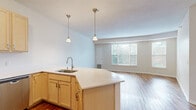 Located in St. Anthony, MN, this two-bedroom, two-bathroom residence offers a well-designed single-level layout with a comfortable and functional floor plan. The open-concept living and kitchen area serves as the heart of the home, where warm hardwood-style flooring extends throughout. The kitchen is equipped with stainless steel appliances, including a refrigerator, range, and microwave, complemented by light wood cabinetry, a tile backsplash, and a generous peninsula with a built-in sink and pendant lighting overhead — ideal for both everyday cooking and casual dining. The living area benefits from multiple windows that invite abundant natural light and views of the surrounding greenery. Both bedrooms are carpeted for comfort, with the spacious primary bedroom offering ample room and natural light through large windows. The two bathrooms are finished with light wood vanities and light countertops; one features a full tub-shower combo with tile surround and hardwood-style flooring. A dedicated closet provides additional storage. Neutral tones and clean finishes throughout create a bright, move-in-ready atmosphere suited to a variety of lifestyles.