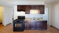 Located at 12500 Fairview Ave in Blue Island, Illinois, this single-floor unit offers a straightforward and functional layout spread across multiple rooms. The kitchen is equipped with rich dark-stained wood cabinetry extending to the upper and lower sections, light granite countertops, a double stainless steel sink, and a black gas range with an overhead ventilation hood — providing ample storage and workspace for everyday cooking needs. Warm wood-look flooring runs consistently throughout the unit, lending a cohesive and clean aesthetic to each room. The bedroom spaces are bright and simply appointed, featuring white walls, natural light admitted through blinded windows, and wall-mounted air conditioning for climate control. The doll-house view reveals a compact but well-organized floor plan with multiple doorways connecting the rooms efficiently. The bathroom includes a vanity with a single basin sink, dark wood cabinetry below, a medicine cabinet mirror, and a full toilet, all finished in a neutral, easy-to-maintain palette with tiled wall accents. Throughout the unit, the clean white walls, consistent flooring, and practical fixtures create a no-frills, move-in-ready living environment suited for comfortable daily living.