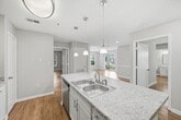 This 910-square-foot, single-floor apartment at 4902 Memory Road in Raleigh, North Carolina offers a well-designed layout with 2 bedrooms, 2 bathrooms, and in-unit laundry. The open-concept kitchen and living area serves as the heart of the home, featuring white shaker cabinets, stainless steel appliances including a refrigerator, range, microwave, and dishwasher, and a peninsula island with a marble-style countertop and undermount sink. The living room is finished with wood-look flooring and a sliding glass door that opens to a private balcony with outdoor views. Both bedrooms are carpeted and receive natural light through large windows with blinds. The primary bedroom measures 170 square feet. Each bathroom is finished with wood-look flooring, a white vanity with a light countertop, a tiled tub-shower combo, and neutral gray walls. A dedicated laundry room houses a full-size side-by-side washer and dryer with overhead wire shelving. Two closets provide additional storage throughout the unit. Neutral gray walls and consistent finishes give the entire space a clean, cohesive aesthetic.