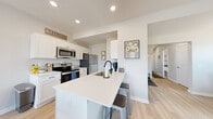 Located at 241 Carlson Lane in Macedon, NY, this well-designed two-story home offers four bedrooms and two bathrooms across two comfortable floors. The main level features an open-concept layout connecting the kitchen, dining room, and living area. The kitchen is appointed with white cabinetry, stainless steel appliances, light wood-tone flooring, and a central island with a built-in sink and bar seating — ideal for both meal prep and casual dining. The adjoining dining area benefits from a sliding glass door that fills the space with natural light and provides outdoor access, complemented by a stylish pendant light fixture overhead. Upstairs, the primary bedroom offers a generous footprint with plush carpeting, neutral tones, and a walk-in closet. The additional bedrooms are equally inviting, with soft carpet, natural light from well-placed windows, and a clean, neutral palette. The two bathrooms are tastefully finished, with one featuring a dark-toned vanity with ample storage and light flooring. A dedicated laundry room on the upper level adds everyday convenience. Throughout the home, light hardwood-style flooring on the main level and soft carpet upstairs create a warm and cohesive aesthetic, while recessed lighting and crisp white walls contribute to a bright, move-in-ready feel.