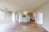Located at 4656 Quigg Dr in Santa Rosa, California, this 2-bedroom, 2-bathroom residence offers a well-designed single-floor layout that maximizes functionality and comfort. The open-concept living and dining area is anchored by light-toned hardwood-style flooring and large windows that invite ample natural light, including a sliding glass door leading to a private balcony with views of surrounding greenery. The kitchen features a peninsula counter with a clean white surface that opens to the main living area, complemented by light wood cabinetry, stainless steel appliances including a refrigerator, gas range, microwave, and dishwasher, along with a built-in sink. Both bedrooms are carpeted for comfort and include closet space; the primary bedroom is generously proportioned with room for substantial furnishings. The two bathrooms are finished in a neutral palette, each including a tub/shower combination and hardwood-style flooring. A dedicated in-unit laundry area houses a full-size washer and dryer with overhead shelving. Hallways connect the rooms efficiently throughout the layout. The overall aesthetic is clean and contemporary, with neutral tones and modern finishes creating a cohesive, move-in-ready environment.