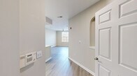 This thoughtfully designed single-floor residence offers a functional and modern living experience across a comfortable footprint. The open-concept layout connects the kitchen and living room seamlessly, creating an inviting flow throughout the main living area. Light gray luxury vinyl plank flooring runs throughout the common spaces, complemented by warm neutral-toned walls and clean white trim that contribute to a bright, cohesive aesthetic.

The kitchen is a standout feature, outfitted with crisp white shaker cabinetry, a classic white subway tile backsplash, quartz countertops, and a full suite of stainless steel appliances including a refrigerator, electric range, and over-the-range microwave. A peninsula provides additional counter space and serves as a natural divider between the kitchen and living area.

The living room receives natural light through a large grid-style window and features a ceiling fan, enhancing comfort year-round. The spacious bedroom is carpeted for warmth and comfort, and includes a set of elegant French doors that open to an outdoor space, allowing for abundant natural light and views. Two closets provide generous storage throughout the unit.

The bathroom is clean and functional, featuring a full tub-shower combination with white tile surround, a vanity, and matching vinyl plank flooring. This unit presents a modern, move-in-ready environment with consistent finishes and practical design throughout.