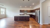 Located at 121 Marigny St in Moncks Corner, South Carolina, this two-story home offers a functional and comfortable layout spread across two generously sized floors. The main level welcomes you through a dedicated entrance that flows into hallways connecting the key living spaces. Rich hardwood flooring extends throughout the main floor, adding warmth and character. The kitchen is a standout feature, showcasing dark espresso cabinetry, granite countertops, stainless steel appliances, and recessed lighting — all designed for both style and practicality. The open kitchen and living room area is bathed in natural light from multiple windows and accented by ceiling fans and a chandelier. A garage with drywall finishing provides additional utility space. Upstairs, the second floor transitions to plush carpeting throughout the bedrooms and a loft-style landing area with recessed lighting. The spacious primary bedroom features a tray ceiling with a ceiling fan, offering a serene retreat. The en-suite bathroom includes granite-topped vanities, wood-look tile flooring, and a walk-in shower with built-in shelving. Additional bedrooms are bright and airy, with large windows allowing ample natural light. The home also includes a dedicated laundry room with a full-size washer and dryer, two closets, and three hallways ensuring seamless connectivity throughout.