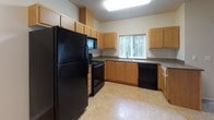 This single-floor residence is thoughtfully designed with an open-concept layout that connects the living area to the kitchen, creating a cohesive and functional living space. The kitchen is well-appointed with warm medium-tone wood cabinetry, dark laminate countertops, and a full suite of black appliances, including a refrigerator, gas range, built-in microwave, and dishwasher. Light tile flooring and a window above the sink allow natural light to brighten the space. A breakfast bar provides a convenient transition between the kitchen and the carpeted living area, which also features a sliding glass door offering additional natural light.

The bedrooms are finished with neutral-toned carpet and feature vertical blind-covered windows that provide ample natural light. The layout includes two bathrooms: one with a single-sink vanity with dark countertops and a tub-shower combination with a sliding glass door, and a second bathroom that also includes a tub-shower and in-unit washer and dryer hookups with cabinetry above. Both bathrooms feature tile flooring. Throughout the unit, neutral wall tones and consistent finishes create a clean, cohesive aesthetic suited for a variety of living arrangements.