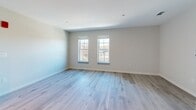 Located at 340 Driftway in Scituate, MA, this one-bedroom, one-bathroom unit offers a thoughtfully designed single-floor layout with modern finishes throughout. Light-toned hardwood-style flooring runs continuously through every room, creating a cohesive and clean aesthetic.

The kitchen is a standout feature, outfitted with white shaker-style cabinetry extending to the ceiling, dark quartz countertops, a subway tile backsplash, and a full suite of stainless steel appliances including a refrigerator, dishwasher, wall oven, and built-in microwave. A central island with a matching dark quartz surface provides additional prep and dining space. Recessed and track lighting illuminate the area effectively.

The open living area adjoins the kitchen and is finished in the same neutral tones, offering a versatile, airy feel. The bedroom features two windows that admit generous natural light and views of the surrounding neighborhood, with a dedicated closet and continued plank flooring.

The bathroom is well-appointed with a vanity, a walk-in shower with glass door enclosure, and coordinating light flooring. A hallway connects the rooms efficiently. The overall design palette—neutral walls, light floors, and modern hardware—creates a clean, contemporary living environment.