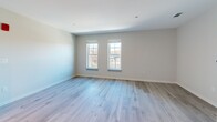 Located at 340 Driftway in Scituate, MA, this one-bedroom, one-bathroom unit offers a thoughtfully designed single-floor layout with modern finishes throughout. Light-toned hardwood-style flooring runs continuously through every room, creating a cohesive and clean aesthetic.

The kitchen is a standout feature, outfitted with white shaker-style cabinetry extending to the ceiling, dark quartz countertops, a subway tile backsplash, and a full suite of stainless steel appliances including a refrigerator, dishwasher, wall oven, and built-in microwave. A central island with a matching dark quartz surface provides additional prep and dining space. Recessed and track lighting illuminate the area effectively.

The open living area adjoins the kitchen and is finished in the same neutral tones, offering a versatile, airy feel. The bedroom features two windows that admit generous natural light and views of the surrounding neighborhood, with a dedicated closet and continued plank flooring.

The bathroom is well-appointed with a vanity, a walk-in shower with glass door enclosure, and coordinating light flooring. A hallway connects the rooms efficiently. The overall design palette—neutral walls, light floors, and modern hardware—creates a clean, contemporary living environment.
