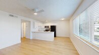 Located at 5009 S West Shore Blvd in Tampa, FL, this two-bedroom, one-bathroom single-floor residence offers a clean, modern interior designed for comfortable everyday living. Light wood-tone flooring flows consistently throughout the space, complementing the crisp white walls and creating a bright, cohesive aesthetic.

The open kitchen and living area serves as the heart of the home. The kitchen is well-appointed with white shaker-style cabinetry, a light quartz peninsula countertop, stainless steel appliances including a range and over-the-range microwave, and a black refrigerator. The peninsula provides additional prep space and naturally connects to the living area, which benefits from natural light via window blinds.

Both bedrooms are generously proportioned with the same wood-tone flooring, ceiling fans, and windows that allow natural light to filter in. The primary bedroom is notably spacious and includes a closet, offering ample storage. The second bedroom mirrors the clean, simple design of the rest of the home.

The bathroom features a full tub-shower combination with clean white tile surround and chrome fixtures. A hallway connects the main living spaces to the private areas of the home. Textured ceilings are present throughout, adding subtle dimension to the otherwise minimalist interior.