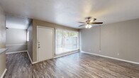 This single-story, 2-bedroom, 2-bathroom residence offers a functional and cohesive layout finished with wood-look laminate flooring throughout. The living room serves as the central gathering space, featuring a ceiling fan with light fixture and a large window dressed with vertical blinds that allows generous natural light to fill the room. A front entry door opens directly into this area, creating an accessible and welcoming flow.

The galley-style kitchen runs parallel along both walls, outfitted with white cabinetry, grey laminate countertops, a stainless steel sink, an electric range, and a full-size refrigerator. Track lighting illuminates the workspace, and an open pantry provides additional storage. The kitchen connects directly to the living area, supporting an open feel between the two spaces.

Both bedrooms are comfortably sized and include ceiling fans with integrated lighting. Each room features a dedicated closet, and the primary bedroom offers added convenience with direct access to a bathroom. The second bedroom also includes closet space and a window for natural light. Both bathrooms include tub/shower combinations with white tile surrounds. A hallway connects the bedrooms and bathrooms, completing the efficient floor plan.