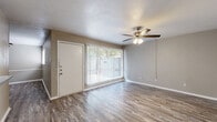 This single-story, 2-bedroom, 2-bathroom residence offers a functional and cohesive layout finished with wood-look laminate flooring throughout. The living room serves as the central gathering space, featuring a ceiling fan with light fixture and a large window dressed with vertical blinds that allows generous natural light to fill the room. A front entry door opens directly into this area, creating an accessible and welcoming flow.

The galley-style kitchen runs parallel along both walls, outfitted with white cabinetry, grey laminate countertops, a stainless steel sink, an electric range, and a full-size refrigerator. Track lighting illuminates the workspace, and an open pantry provides additional storage. The kitchen connects directly to the living area, supporting an open feel between the two spaces.

Both bedrooms are comfortably sized and include ceiling fans with integrated lighting. Each room features a dedicated closet, and the primary bedroom offers added convenience with direct access to a bathroom. The second bedroom also includes closet space and a window for natural light. Both bathrooms include tub/shower combinations with white tile surrounds. A hallway connects the bedrooms and bathrooms, completing the efficient floor plan.
