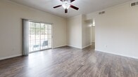 Located at 1900 Aquarena Springs Dr in San Marcos, TX, this single-floor, 3-bedroom, 2-bathroom home offers a practical and well-appointed layout. The open-concept living, dining, and kitchen area forms the heart of the home, featuring durable wood-look flooring, crown molding, and a ceiling fan with light fixture. The kitchen is equipped with stainless steel appliances — including a refrigerator, range, and microwave — rich dark-brown cabinetry, a tile backsplash, and a peninsula with an integrated sink that doubles as a breakfast bar. The dining area comfortably accommodates a table and chairs beneath a pendant light. Two of the three bedrooms are finished with plush carpet and ceiling fans, each featuring a window that brings in natural light. The third bedroom features wood-look flooring. The bathrooms include dark-wood vanities with light countertops, wood-look tile flooring, and a full tub-shower combination. A dedicated laundry room provides washer and dryer hookups with overhead shelving. Five closets throughout the home offer generous storage. The covered patio provides outdoor seating and views of the surrounding tree-lined neighborhood. A hallway connects the private quarters seamlessly to the main living space.