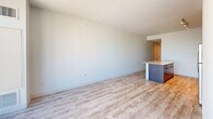 Located in the heart of downtown Austin at 501 Brazos St, this well-appointed one-bedroom, one-bathroom residence offers a thoughtfully designed layout with modern finishes throughout. Light wood-style flooring flows seamlessly across the entire space, creating a bright, cohesive aesthetic.

The open-concept living area is anchored by a kitchen island with a wood-paneled base and light countertop, providing both workspace and casual seating. The kitchen features stainless steel appliances and contemporary cabinetry, flowing naturally into the spacious living area.

The generously sized bedroom is a standout feature, offering ample room for comfortable furnishing. It includes a ceiling fan and is accessed via a striking frosted glass barn door with a sleek black metal frame — a modern design element that adds both style and functionality. The bedroom connects directly to a large walk-in closet outfitted with floor-to-ceiling adjustable wire shelving and hanging rods for versatile storage.

The bathroom is clean and contemporary, featuring light wood flooring, a glass-enclosed walk-in shower with dramatic dark tile surround, and minimalist fixtures with matte black hardware accents.

A hallway with louvered closet doors and a ceiling vent leads from the main living area toward the bedroom, with natural light visible from the end, suggesting an exterior-facing window or door.