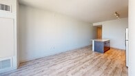 Located in the heart of downtown Austin at 501 Brazos St, this well-appointed one-bedroom, one-bathroom residence offers a thoughtfully designed layout with modern finishes throughout. Light wood-style flooring flows seamlessly across the entire space, creating a bright, cohesive aesthetic.

The open-concept living area is anchored by a kitchen island with a wood-paneled base and light countertop, providing both workspace and casual seating. The kitchen features stainless steel appliances and contemporary cabinetry, flowing naturally into the spacious living area.

The generously sized bedroom is a standout feature, offering ample room for comfortable furnishing. It includes a ceiling fan and is accessed via a striking frosted glass barn door with a sleek black metal frame — a modern design element that adds both style and functionality. The bedroom connects directly to a large walk-in closet outfitted with floor-to-ceiling adjustable wire shelving and hanging rods for versatile storage.

The bathroom is clean and contemporary, featuring light wood flooring, a glass-enclosed walk-in shower with dramatic dark tile surround, and minimalist fixtures with matte black hardware accents.

A hallway with louvered closet doors and a ceiling vent leads from the main living area toward the bedroom, with natural light visible from the end, suggesting an exterior-facing window or door.