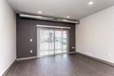 This single-floor unit offers a thoughtfully designed layout that balances functionality with modern aesthetics. The open living area features rich dark hardwood-style flooring, recessed lighting, and a textured ceiling. A prominent dark accent wall frames a large sliding glass door dressed with vertical blinds, allowing natural light to fill the space while providing outdoor access. Exposed ductwork adds an industrial touch to the interior.

The kitchen is well-appointed with white cabinetry, granite-style countertops, a tile backsplash, and a full suite of stainless steel appliances including a refrigerator, range, microwave, and dishwasher. The layout flows seamlessly into the open living and dining area, making it ideal for everyday living.

The bedroom is finished with plush carpet, a ceiling fan, and a window that brings in natural light and exterior views. Adjacent to the bedroom, the bathroom features a white vanity with granite-style countertops, ample cabinet storage, a large mirror, and a walk-in shower with a curtain enclosure. Throughout the unit, consistent gray-toned trim and doors provide a cohesive, contemporary finish that ties each space together.