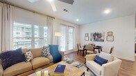 Located in Spring, TX, this well-appointed single-floor residence offers a thoughtfully designed layout that balances modern style with everyday functionality. The open-concept living and dining area is bathed in natural light, courtesy of large windows and French doors that lead to an outdoor view of the surrounding community. Wood-look flooring, a ceiling fan, and clean white walls contribute to an airy, welcoming atmosphere.

The kitchen is a standout feature, showcasing rich wood-toned cabinetry, a striking granite-topped island with bar seating, stainless steel appliances — including a French door refrigerator, microwave, and range — and a white tile backsplash. Stylish pendant lighting adds a refined finishing touch overhead.

The bedroom is a calm retreat, carpeted for comfort, with a large window providing natural light and outdoor views. It connects directly to a generously sized walk-in closet with dual hanging rods and shelving for ample storage.

Two bathrooms serve the residence, each featuring warm wood-finish vanities, tile flooring, and modern fixtures. The primary bathroom includes an oversized walk-in shower with large-format tile, while a second bathroom offers a tall storage cabinet alongside the vanity. The overall design is clean, contemporary, and move-in ready.
