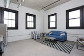 This single-floor residence showcases a compelling blend of industrial heritage and contemporary design. The living area is defined by painted white brick walls and black-framed windows that fill the space with natural light while offering open sky views. Polished concrete flooring runs throughout, reinforcing the unit's urban aesthetic.

The kitchen is well-appointed with white shaker-style cabinetry, granite countertops, and a full suite of stainless steel appliances, including a refrigerator, electric range, over-the-range microwave, and dishwasher. A stainless steel sink with a modern faucet completes the functional workspace, and an in-unit washer and dryer are also present.

The bedrooms feature neutral tones with soft carpeting underfoot. One bedroom benefits from exposed brick detailing and a large window, while the other offers a quieter, more streamlined feel with gray walls and clean finishes.

Two bathrooms serve the unit. One features tile flooring, a white vanity, and a walk-in shower, while the second includes a soaking tub, tiled floors, a white vanity with storage, and a black-framed window that brings in natural light. The overall ambiance is modern and industrial, with a cohesive palette of neutrals throughout.