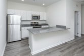Located in Warren, Michigan, this two-floor residence offers a well-designed layout with modern finishes throughout. The kitchen is a standout feature, equipped with stainless steel appliances including a refrigerator, range, and built-in microwave, all complemented by granite countertops and crisp white cabinetry. A peninsula with an undermount sink adds both functionality and workspace to the kitchen area. Light wood-tone flooring runs consistently through the main living areas, creating a cohesive and clean aesthetic. The bedrooms are generously sized, featuring large windows with blinds that allow ample natural light to fill the rooms. Closet space is well accommodated with double-door closets offering built-in hanging rods. The bathrooms are finished with granite-topped vanities; a primary bath features dual opposing vanities with undermount sinks and access to a dedicated laundry area. A secondary bathroom includes a full soaking tub and shower combination. An included in-unit stacked washer and dryer provides added convenience. The attached garage offers a spacious concrete-floor bay with an automatic opener. Throughout the home, neutral wall tones, recessed lighting, and consistent flooring choices create a bright, move-in-ready environment.