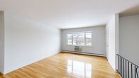 Located at 6 Jackman Dr in Poughkeepsie, NY, this two-bedroom, one-bathroom unit offers a well-organized and functional layout with a clean, neutral aesthetic throughout. Gleaming hardwood floors run continuously across the living areas and bedrooms, reflecting natural light and lending a bright, open feel to the space.

The two living areas provide flexible options for both relaxing and entertaining. Each bedroom is comfortably sized, with the primary bedroom offering a generous footprint, large enough to accommodate standard furnishings. Both bedrooms feature windows that invite natural light and offer views of the surrounding neighborhood. Two dedicated closets provide ample storage throughout the unit.

The kitchen is equipped with warm-toned wood cabinetry, granite-style countertops, and tile flooring, with a window that overlooks the exterior. The bathroom features classic white tile flooring, a shower-tub combination, and a window for natural ventilation and light.

A secondary living area with an exterior door and an adjacent window opens to views of a balcony railing, providing a convenient secondary entry point. Baseboard heating is present throughout the unit. The ornate iron staircase railing visible in one of the living areas adds a subtle decorative touch to the overall interior.