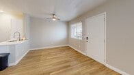 Located at 60 W Stone Loop in Tucson, Arizona, this efficiently designed single-floor studio offers a clean, modern aesthetic with thoughtful use of space. Warm-toned luxury vinyl plank flooring runs throughout, complementing the soft neutral wall palette and crisp white baseboards that give the unit a bright, cohesive feel.

The open-concept kitchen and living area forms the heart of the space. The kitchen is outfitted with white shaker-style cabinetry, white quartz countertops, a subway tile backsplash, and a full suite of stainless steel appliances including a refrigerator, electric range, and over-the-range microwave. A peninsula counter provides additional prep space and visually separates the kitchen from the living area. Recessed lighting ensures the kitchen is well-lit, while a ceiling fan with integrated lighting serves the living area. A window with blinds allows natural light to filter in, and a keypad-secured entry door adds a modern convenience.

The bathroom is finished with white subway tile surrounding the tub-shower combo, a white vanity with a single sink, and coordinating wood-look flooring, creating a clean and functional space. A dedicated closet provides practical storage. The overall design prioritizes functionality and modern simplicity, making this Tucson studio an efficient and well-appointed living space.